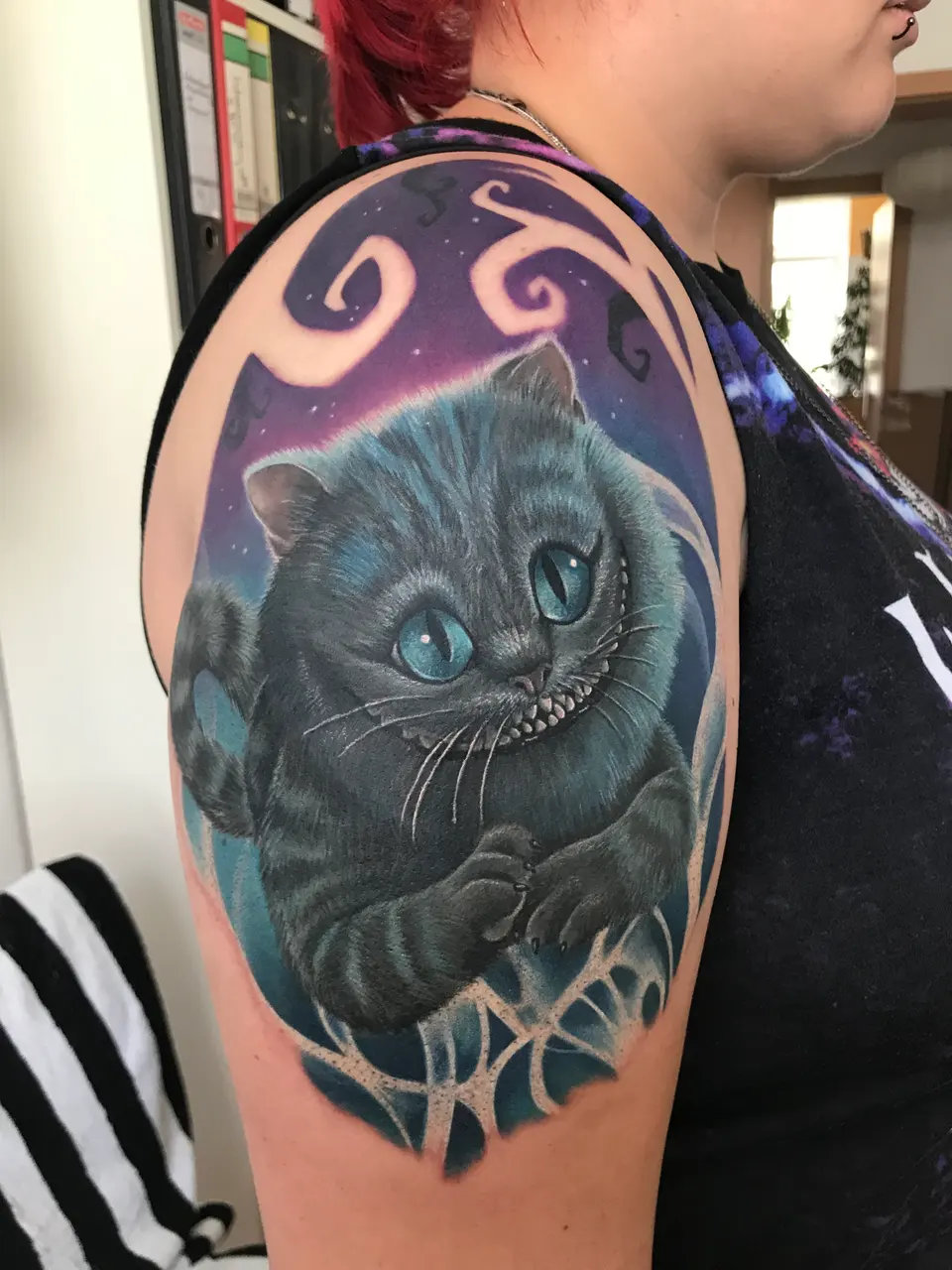 Grinsekatze vor Mond als Schulter-Tattoo